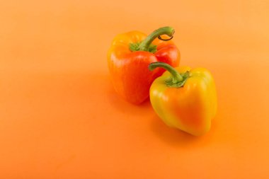 Tatlı bellpepper. Turuncu bir arka plan üzerinde iki turuncu-sarı tatlı bellpeppers. İki parça. Stüdyo ışık. Üstten görünüm