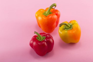 Tatlı bellpepper. İki portakal-sarı ve pembe bir arka plan üzerinde kırmızı bir tatlı bellpeppers. Üç parça. Stüdyo ışık. Üstten görünüm