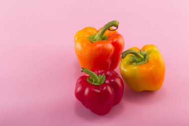 Tatlı bellpepper. İki portakal-sarı ve pembe bir arka plan üzerinde kırmızı bir tatlı bellpeppers. Üç parça. Stüdyo ışık. Üstten görünüm