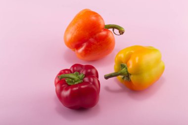 Tatlı bellpepper. İki portakal-sarı ve hafif pembe bir arka plan üzerinde kırmızı bir tatlı bellpeppers. Üç parça. Stüdyo ışık. Üstten görünüm