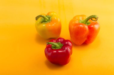 Tatlı bellpepper. İki portakal-sarı ve sarı bir arka plan üzerinde kırmızı bir tatlı bellpeppers. Üç parça. Stüdyo ışık. Üstten görünüm