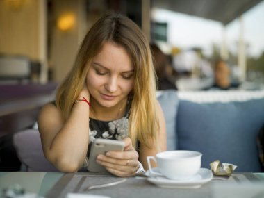 Yazlık kafede akıllı telefonu olan bir kız.