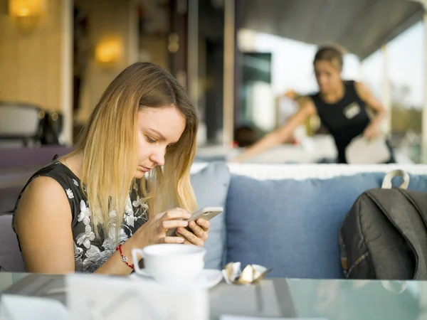 Девушка со смартфоном в летнем кафе — стоковое фото