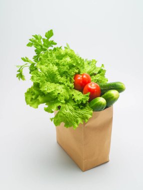 Sebze salatası için çeşitli malzemeler. Taze toplanmış yeşillikler ve sebzeler beyaz bir arka planda bir kesekağıdında. Marul, maydanoz, dereotu, domates, salatalık. Tahsilat. Hazır ol. Sağlıklı yiyecekler. Yaşam biçimi