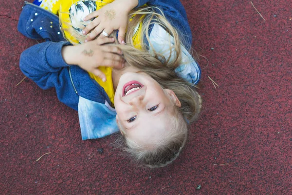 Szczęśliwa Biała Dziewczyna Długimi Blond Włosami Leży Placu Zabaw Przytula — Zdjęcie stockowe