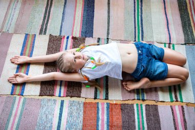 Beyaz tişörtlü beyaz kız yoga yapıyor, çizgili kumaş halıyla evde geriniyor. Dijital detoks, doğayla birleşme, sağlıklı kırıklar. Evde spor yapıyor, yaşam tarzı....