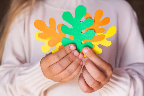 Orange, yellow and green oak leaves cut from paper in children\'s hands close-up. The concept of caring for nature, environmental friendliness, eco. Activities with children, crafts. Autumn colors