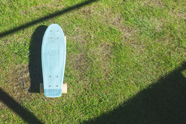 Niebieska deskorolka Penny Board na zielonym trawniku, trawa. Aktywny tryb życia, sprzęt sportowy. Pocisk do sztuczek, skoków. Teren sportowy. Przestrzeń kopiowania. — Zdjęcie stockowe