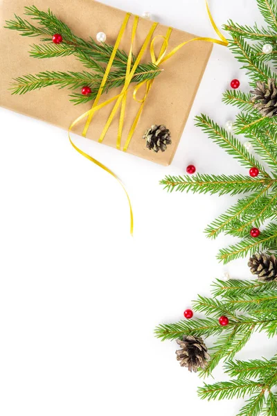 Різдвяний подарунок у ремісничому папері, пов'язаний золотою стрічкою з гілкою ялини, гілки ялинки на білому тлі. Плоска покладена — стокове фото
