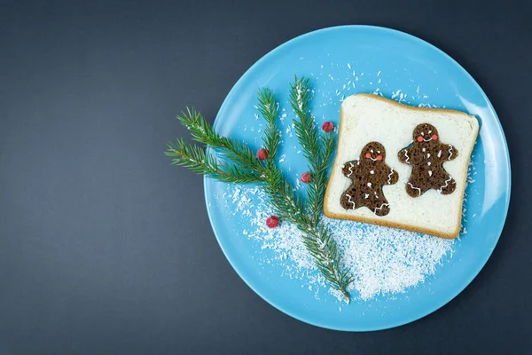 Pan tostado, hombres de jengibre, rama de abeto en plato azul, fondo oscuro.Navidad, año nuevo.Desayuno, comida creativa — Foto de Stock