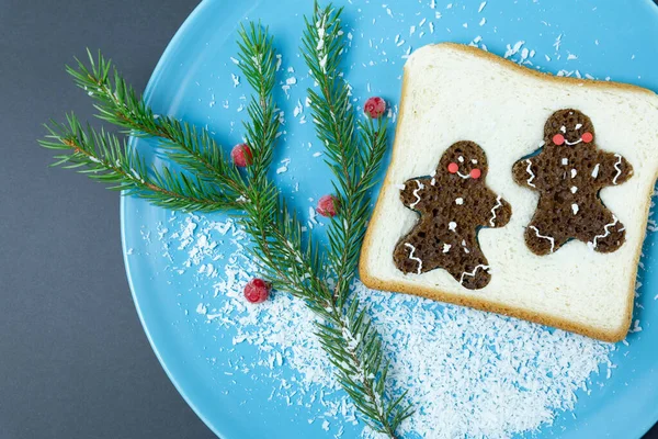 Pan tostado, hombres de jengibre, rama de abeto en un plato azul. Navidad, año nuevo. Desayuno festivo, comida creativa. — Foto de Stock