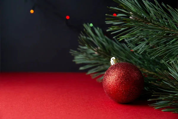 Соснова гілка і червоний різдвяний м'яч крупним планом на червоно-чорному тлі. Новорічний або різдвяний фон, листівка . — стокове фото