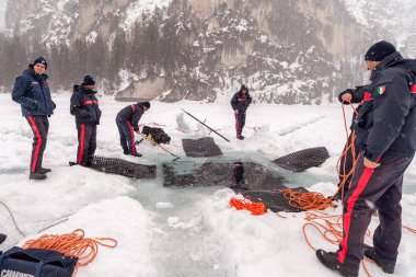 Braies Lake, İtalya - 10 Mart 2018: İtalyan Carabinieri kazmak büyük bir delik derin içine girerek kurtarma dalgıçlar göle, Braies, İtalya için buz