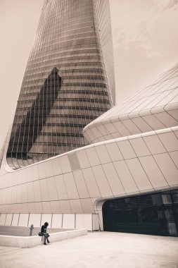 Milan, İtalya - 29 Nisan 2018: Genç kız yalnız Hadid kule tarafından Zaha Hadid mimarlar, Milan ' ın yakın modern Citylife bölge oturmuş
