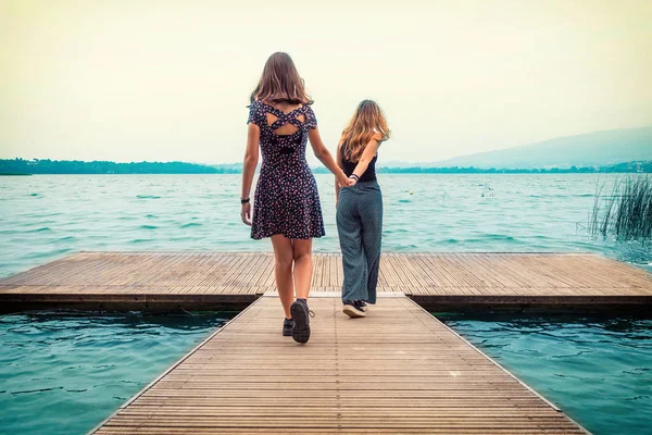 İki genç kız kardeşi Gölü, Pusiano Gölü, Lecco, İtalya doğru yürüyen iskele üzerinde