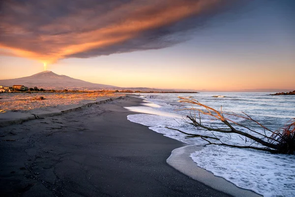 The spectacular volcanic ash plume generated by volcano Mt. Etna during the last eruption of December 2018 viewed from the coastline beach of Catania, Sicily, Italy