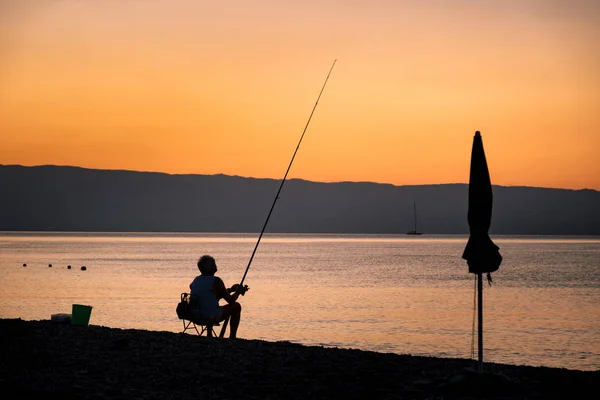 Fisherman on beach at sunrise Stock Image