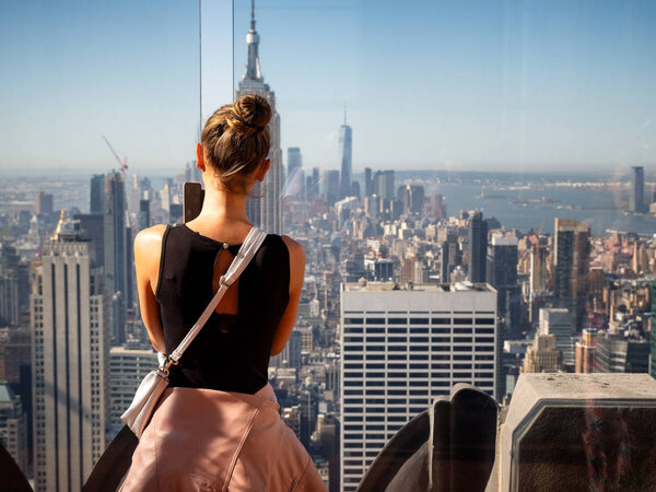 Cute girl taking photos of the Skyline of Manhattan with the Empire State Building in front, New York, USA