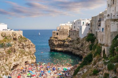 Historic cliffside houses above turquoise Adriatic waters in Polignano a Mare, Apulia, Italy. Iconic summer seascape, tourism and lifestyle destination.
