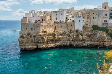 Historic cliffside houses above turquoise Adriatic waters in Polignano a Mare, Apulia, Italy. Iconic summer seascape, tourism and lifestyle destination.