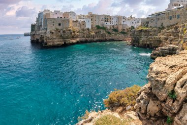 Historic cliffside houses above turquoise Adriatic waters in Polignano a Mare, Apulia, Italy. Iconic summer seascape, tourism and lifestyle destination.