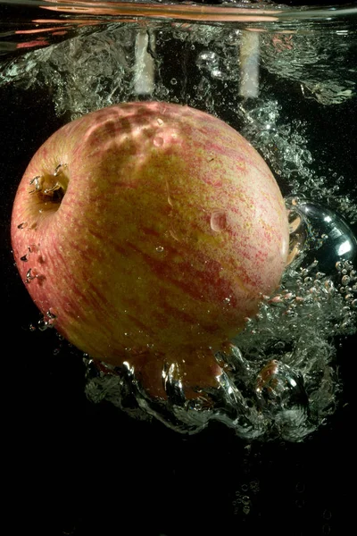 水の流れの赤いりんご 水と黒の背景の空気の流れの中の赤いりんご 水の落下のアップルからはね 水の中の赤いリンゴ 水の流れのフルーツ — ストック写真