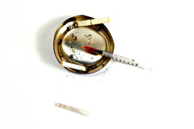 Şırınga ve birkaç sigara izmaritleri (üzerinde beyaz izole doğaçlama bir kül tablası üzerinde)