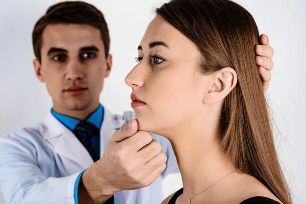 Doctor, male, viewing profile of the patient to assess the curvature of the nose and the symmetry of the lips. Close up.