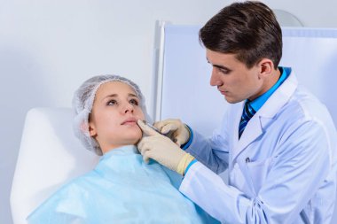 Kozmetik uzmanının elleri yüzüne ve dudaklarına iğne yapıyor. Genç bir kadın güzellik salonunda yüz aşısı yaptırıyor. Yaşlanma, gençleşme ve hidrasyon prosedürleriyle yüzleş. Estetik kozmetoloji. Kapat..