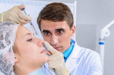 Kozmetik uzmanının elleri yüzüne ve dudaklarına iğne yapıyor. Genç bir kadın güzellik salonunda yüz aşısı yaptırıyor. Yaşlanma, gençleşme ve hidrasyon prosedürleriyle yüzleş. Estetik kozmetoloji. Kapat..