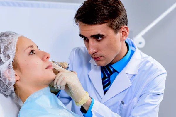 Hands of cosmetologist making injection in face, lips. Young woman gets beauty facial injections in salon. Face aging, rejuvenation and hydration procedures. Aesthetic cosmetology. Close up.