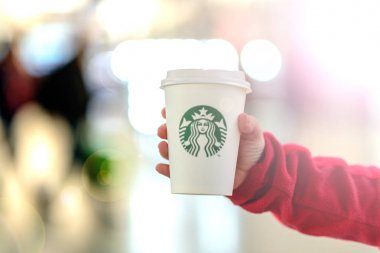 Çocuk bulanık karşı bir fincan Starbucks içecek tutuyor