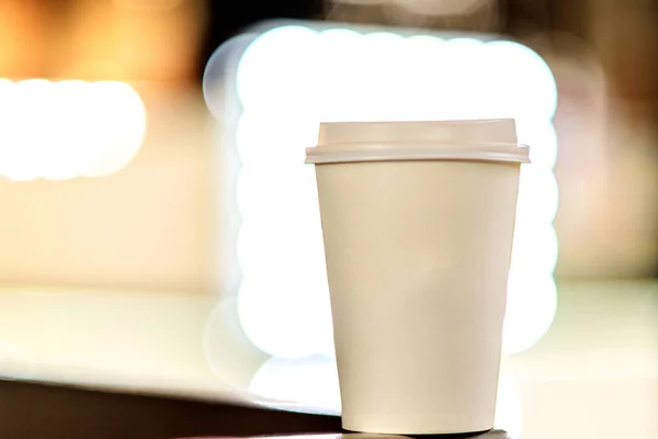 A white paper cup with coffee from against the background of the