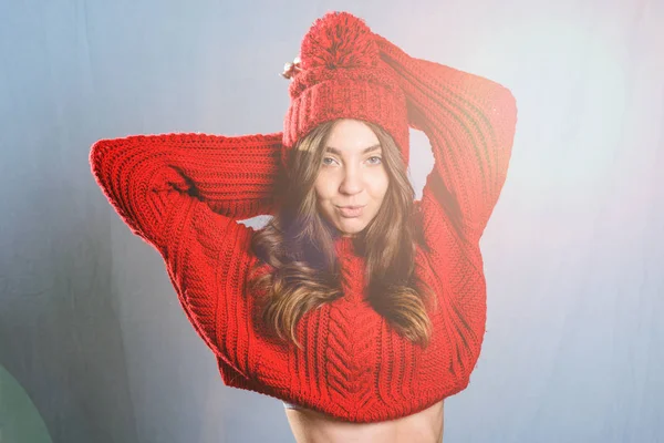 Piękna, młoda kobieta w czerwonym sweter z dzianiny i kapelusz na szarym ba — Zdjęcie stockowe