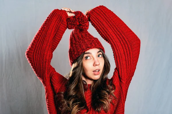 Piękna, młoda kobieta w czerwonym sweter z dzianiny i kapelusz na szarym ba — Zdjęcie stockowe