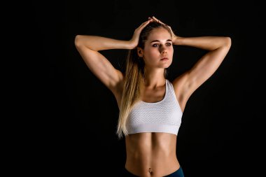 Şarj minderinde spor üniformalı genç bir kadın. Siyah arkaplanda büyüyen bir portre