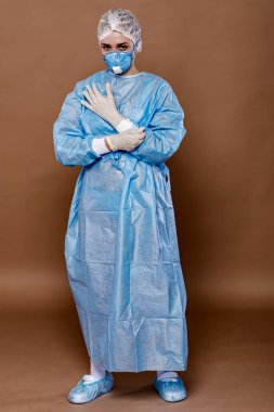 Coronavirus konsepti. COVID-19. Koruyucu takım elbiseli genç bayan doktor, yüz maskesi ve lastik eldiven (şeftali arka planda izole)