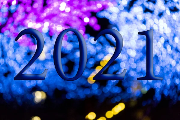 Text with the year number 2021 with a background of bright blue lights out of focus with Bokeh effect. Happy New Year 2021.
