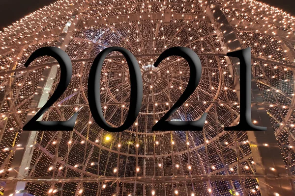 Text with the year number 2021 with a background of bright blue lights out of focus with Bokeh effect. Happy New Year 2021.