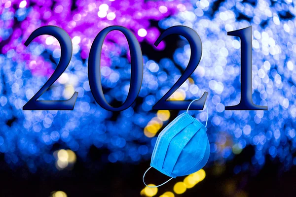 文字与2021年的编号 背景是焦虑症的明亮蓝光与Bokeh效果和一次性蓝色卫生面罩 2021年新年快乐 — 图库照片