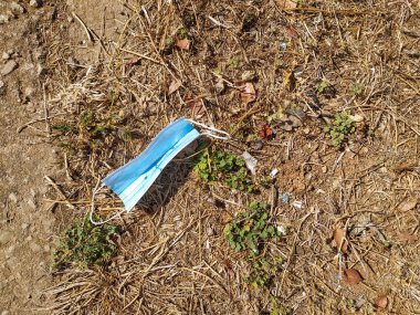 Doğanın ortasında duran mavi yüz maskesi. Coronavirüs salgını tarafından üretilen atık, Covid-19