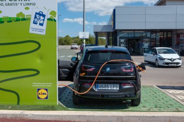 Campos. Balearic Adaları / İspanya; Ağustos 2020: koyu renkli elektrikli araba bir süpermarket otoparkındaki şarj noktasında şarj oluyor