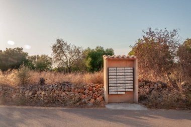 Gün batımında Akdeniz doğasıyla çevrili bir yolun ortasında posta kutuları. Mallorca Adası, İspanya