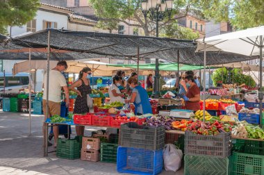 Campos, Balear Adaları / İspanya; Ağustos 2020: Campos 'taki geleneksel sokak pazarında meyve ve sebze tezgahı. Covid-19 'un yeni sosyal önlemleri için eldiven ve maskeli satıcı ve alıcılar