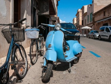 Campos, Balear Adaları / İspanya; Eylül 2020: Açık mavi Vespa 50 motosiklet Campos köyünde bazı bisiklet ve arabaların yanına park edilmiş.