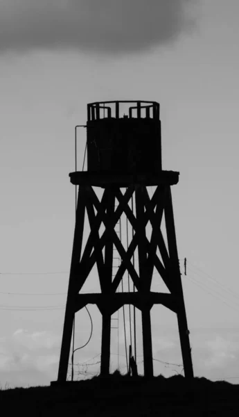 Gölgedeki eski bir su kulesinin siyah beyaz resmi.