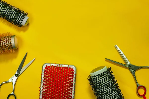 hair brushes and scissors on the bright yellow background