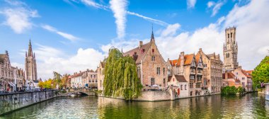 Tarihi evleri, kilisesi, çan kulesi ve Belçika 'nın Bruges kentindeki ünlü kanalı ile panoramik şehir manzarası.
