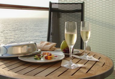 Kutlama konsepti: Aperatifli şampanya ve yolcu gemisinin balkonunda meyve. 
