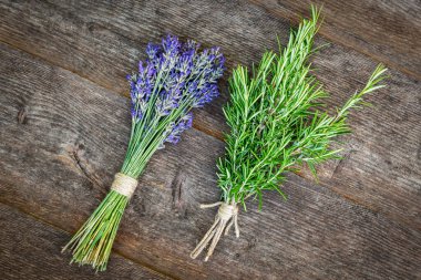 Aromatik ve homeopatik bitkiler. Ahşap bir masada lavanta ve biberiye demetleri.